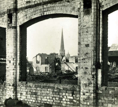 The surviving spire of Christ Church framed by the unglazed window of a destroyed factory.